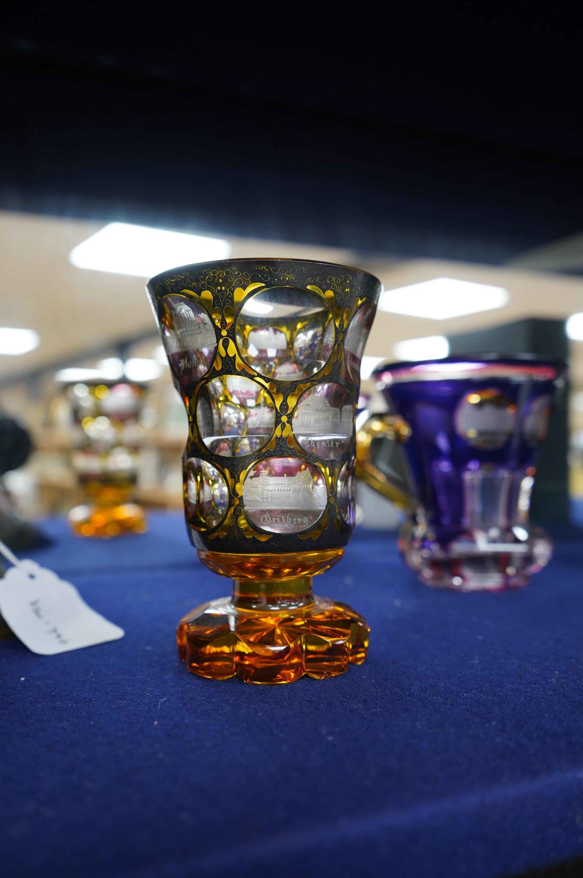 A 19th century Bohemian overlaid glass vase engraved with topographical views and a similar cup. Condition - good.